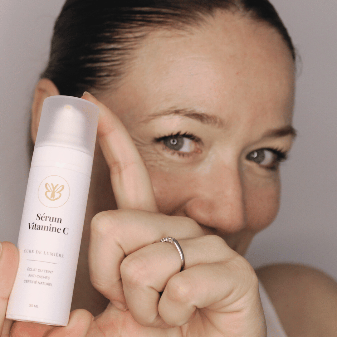 Claire souriante tenant le sérum éclat à la vitamine C, soin lumière pour peaux ternes après 40 ans